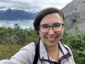 Headshot of Kate Rae Davis hiking in mountains.