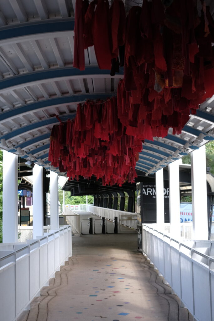 Outdoor art exhibit. Red fabric hanging down from top of covered walkway.